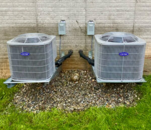 Two Carrier outdoor AC condenser units installed on wall mounts by Infinite Heating & Air in Newnan, GA.