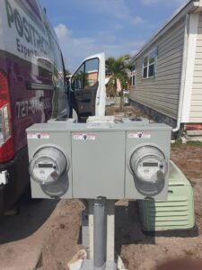 Two outdoor electricity meters installed on a pole with a Positricity service van in the background in Clearwater, FL.