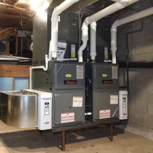 Two Amana furnaces or air handlers installed side-by-side in a basement by PureTemp Heating and Cooling in Salem, NH.