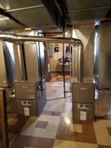 Two new Lennox furnaces or air handlers installed side-by-side in a residential basement by Shook Heating And Cooling in Livonia, MI.