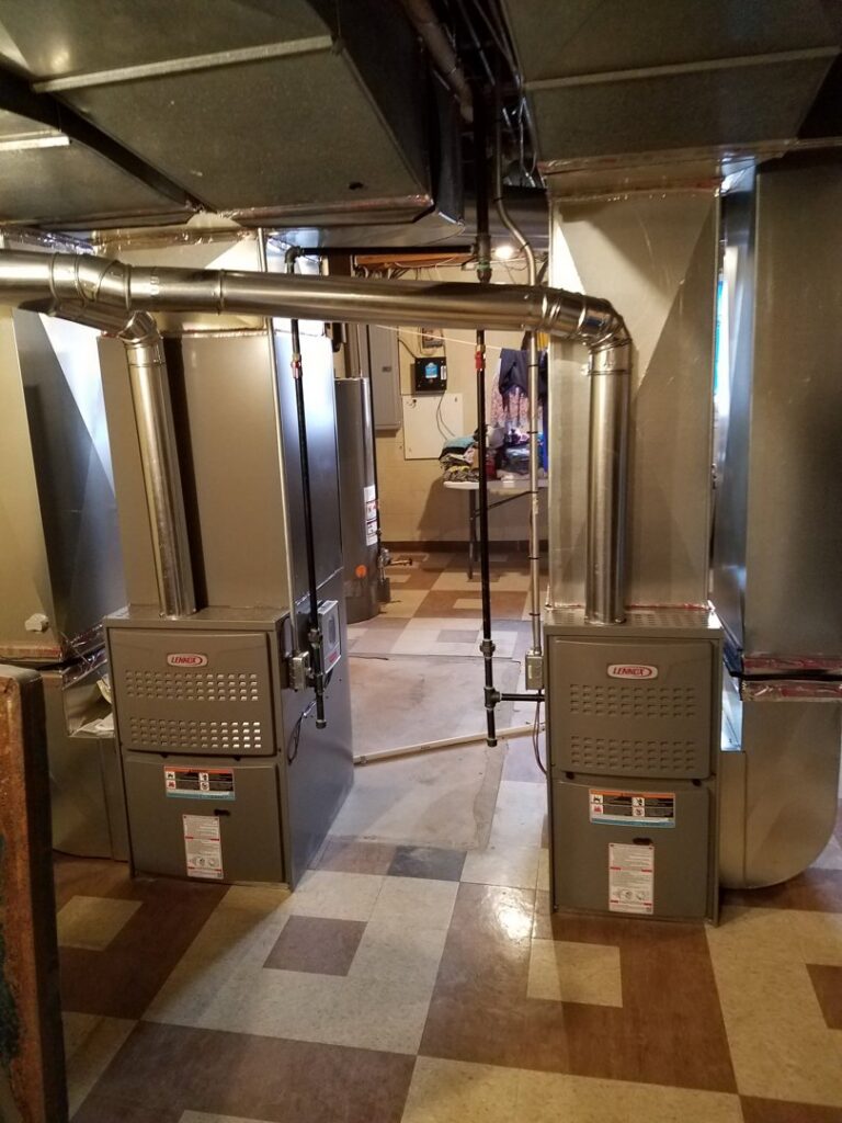 Two new Lennox furnaces or air handlers installed side-by-side in a residential basement by Shook Heating And Cooling in Livonia, MI.
