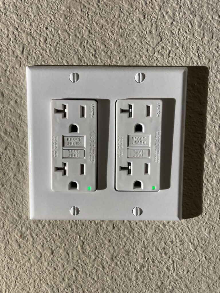 Two GFCI outlets installed side-by-side on a textured wall by Delatour Electric in Portland, OR.