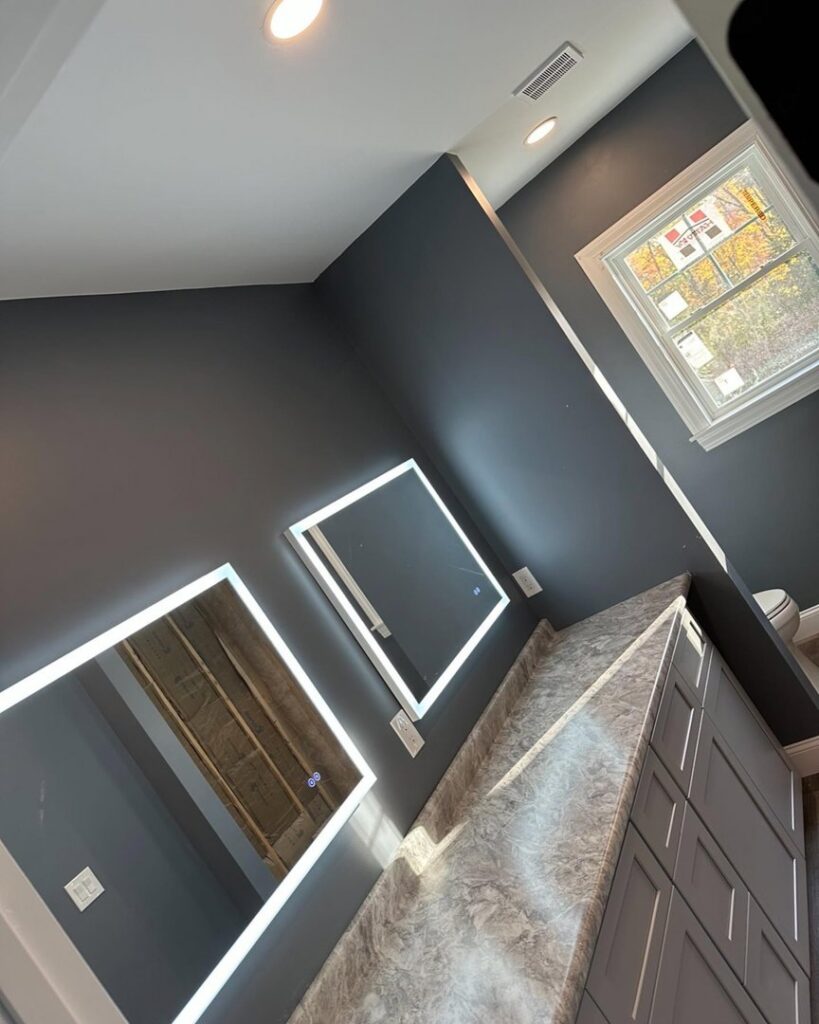 Dual LED-lit mirrors and recessed lighting installed in a modern bathroom by Breakers Electric LLC in Dover, NH.