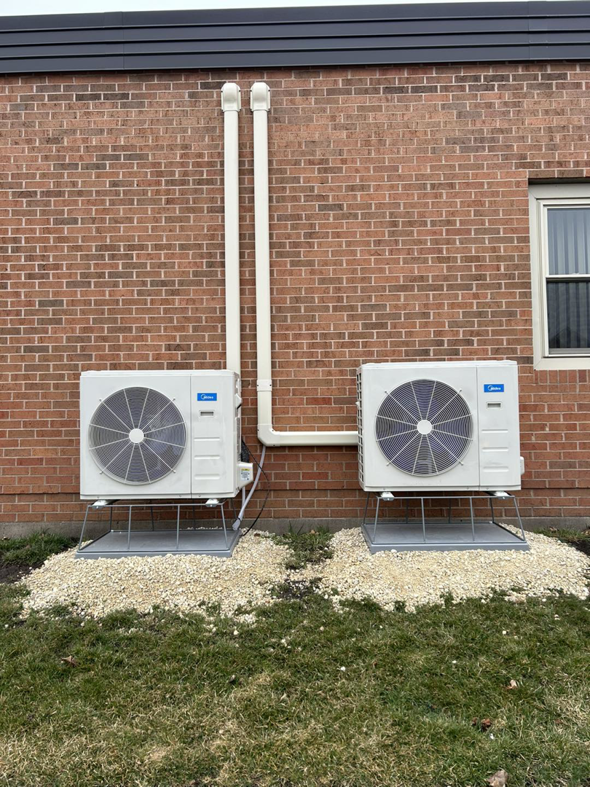 Two Midea mini-split outdoor condenser units installed on a brick building by BRY Heat and Air in Elgin, MN