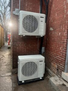Two outdoor mini-split condenser units installed on a brick wall by GrinHouse HVACR in La Grange, KY.