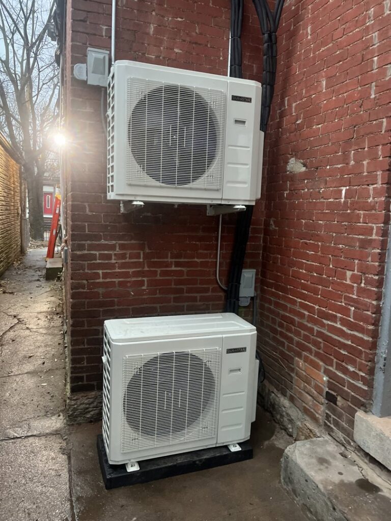 Two outdoor mini-split condenser units installed on a brick wall by GrinHouse HVACR in La Grange, KY.
