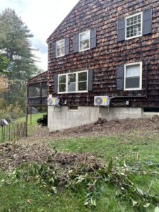 Two outdoor HVAC units professionally installed on the side of a residential building by Laird's HVAC in Auburn, ME.