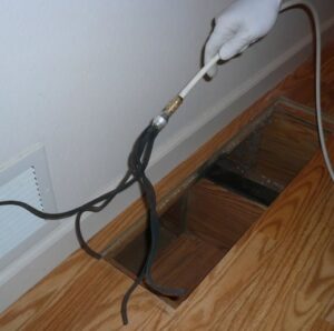 A hand performing duct cleaning service by inserting a tool into a floor vent, offered by The Right Flow Heating and Air LLC in Lawton, OK