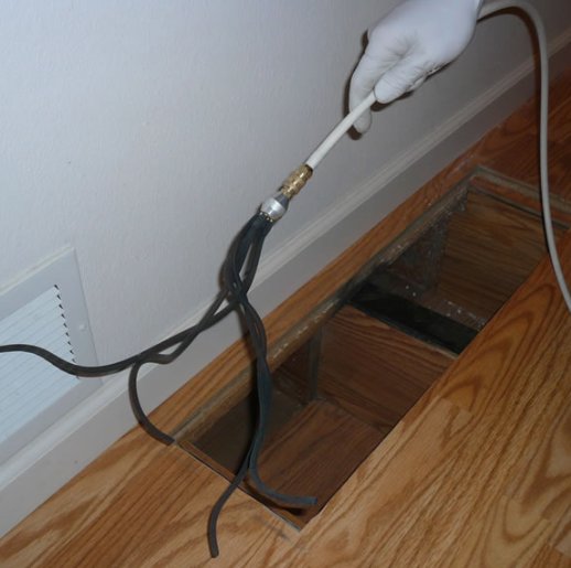 A hand performing duct cleaning service by inserting a tool into a floor vent, offered by The Right Flow Heating and Air LLC in Lawton, OK