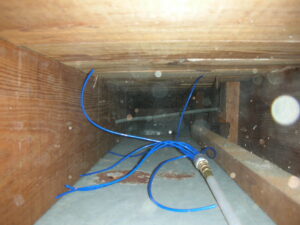 A specialized duct cleaning tool with blue hoses inserted into a wooden air duct, demonstrating work by Fresh N Clean Duct Cleaning in Arvada, CO.