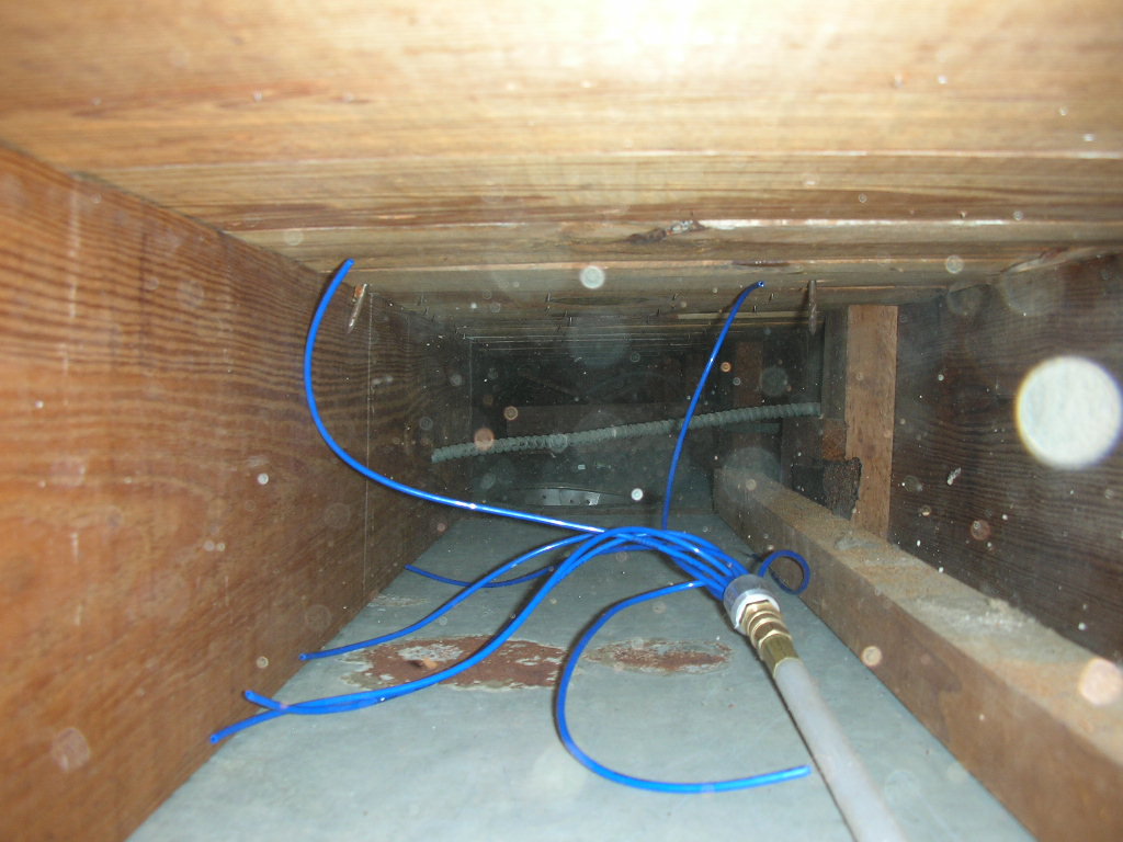 A specialized duct cleaning tool with blue hoses inserted into a wooden air duct, demonstrating work by Fresh N Clean Duct Cleaning in Arvada, CO.