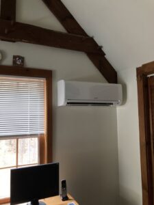 A white ductless mini-split indoor unit installed high on a wall in a room, expertly done by A&D Ductless LLC in Lunenburg, MA.