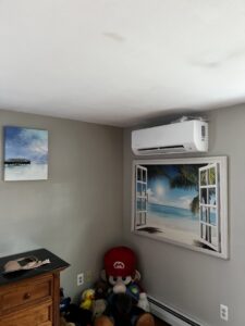 A ductless mini-split unit installed on a wall in a room with a decorative window, a service provided by A&D Ductless LLC in Lunenburg, MA.