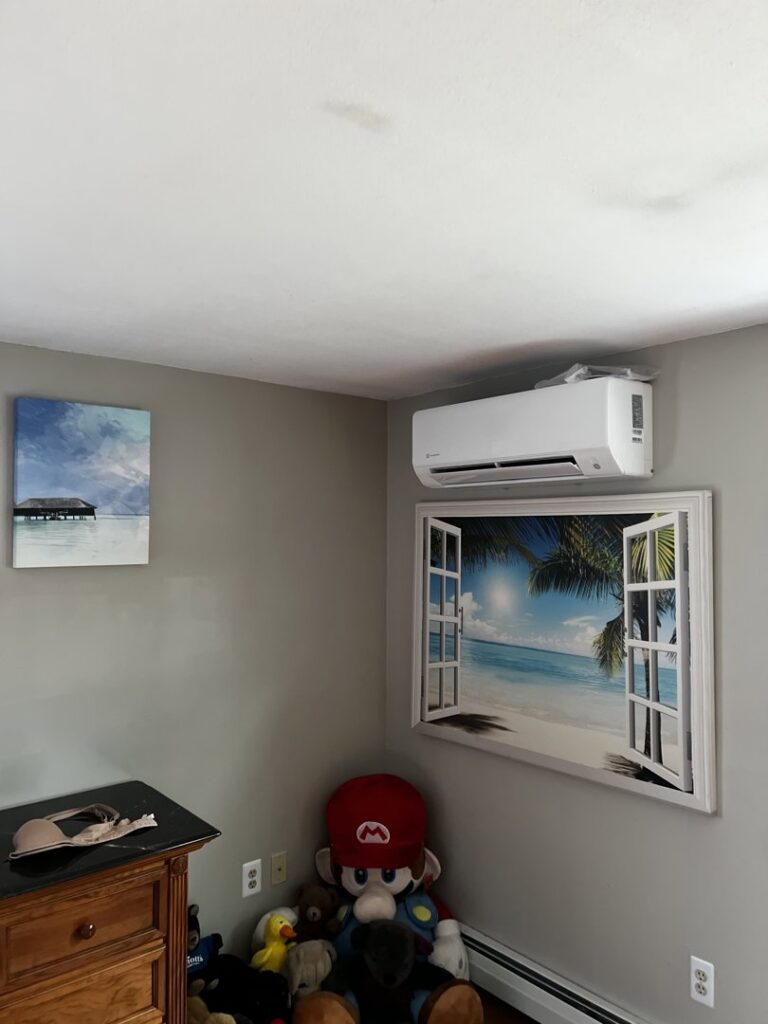 A ductless mini-split unit installed on a wall in a room with a decorative window, a service provided by A&D Ductless LLC in Lunenburg, MA.