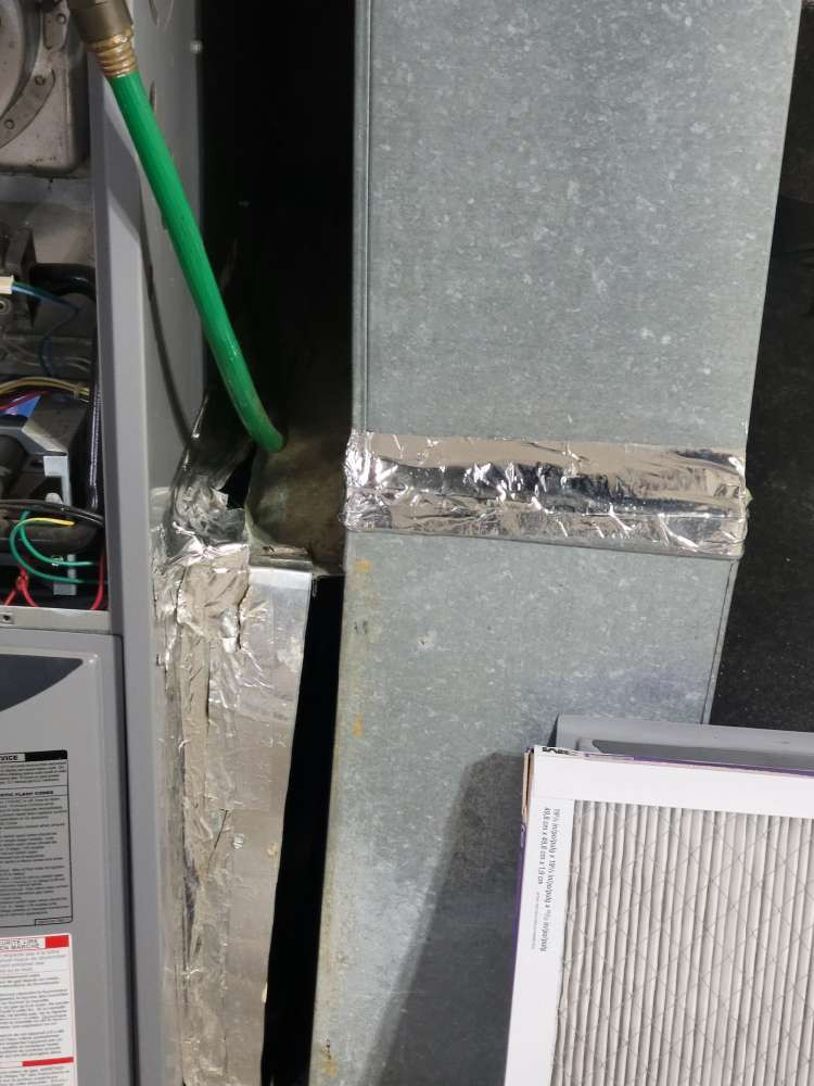 A close-up view of ductwork connecting to a furnace unit with a hose and air filter by Friess Heating & Air Conditioning in Topeka, KS
