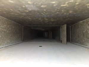 An interior view of a dusty air duct before cleaning, demonstrating the services of Pro Power Air Duct & Dryer Vent Cleaning in Kenosha, WI.