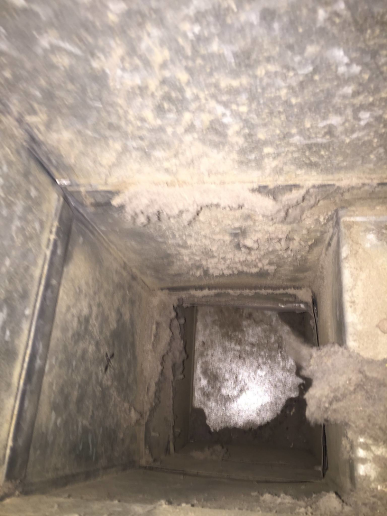 An interior view of a dusty air duct showing debris buildup by Richmond Restoration in Worcester, MA