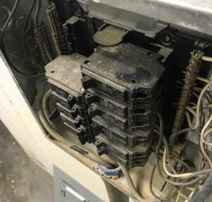 A close-up view of a dusty electrical panel with multiple circuit breakers, requiring maintenance from AK Electrical, LLC in Mesquite, TX.