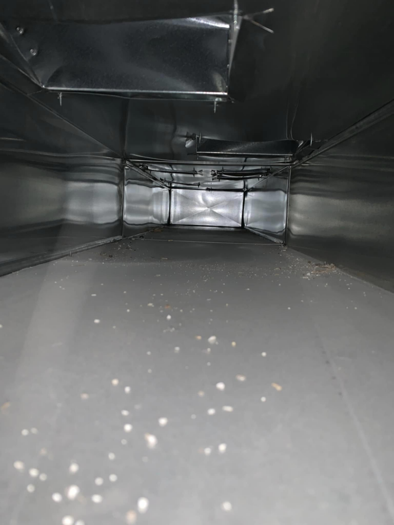 The dusty interior of a rectangular air duct, ready for professional cleaning by Air Duct Solutions in Waukee, IA.
