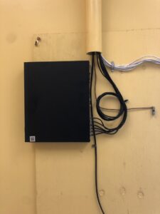 A DVR/NVR security system box mounted on a yellow wall with organized cabling, installed by PTech Installs in Columbus, GA.