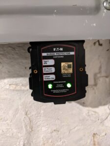 An Eaton surge protector with green status lights, installed in an electrical panel by Jeremy Electrical in Roeland Park, KS.