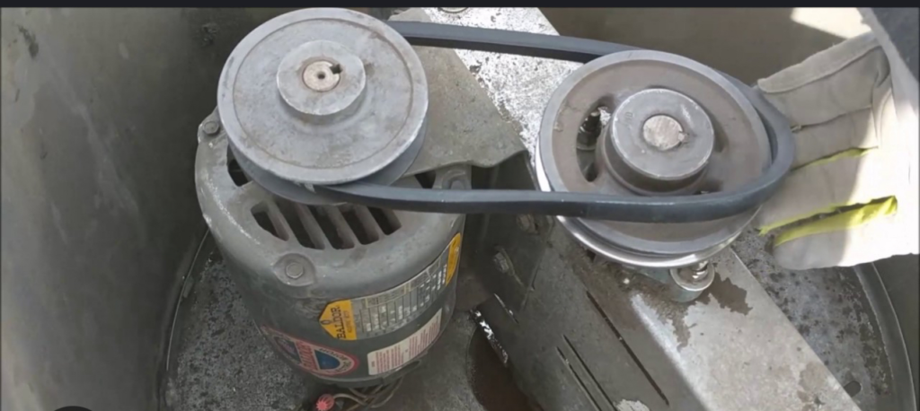 An electric motor with a belt and pulleys, serviced by Wire That Up-Fire Suppression & Hood Electrical in Suffolk, VA.
