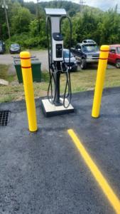 An electric vehicle charging station with yellow safety bollards installed by Pittsburgh Electric & Maintenance in Pittsburgh, PA