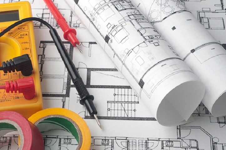 Electrical blueprints, a multimeter, and tape, essential tools for Corbin & Maille, Inc electricians in Erie, PA.