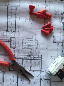 Electrical blueprints, wire nuts, pliers, and an outlet for Cothern Electric, LLC in Jonesboro, AR.