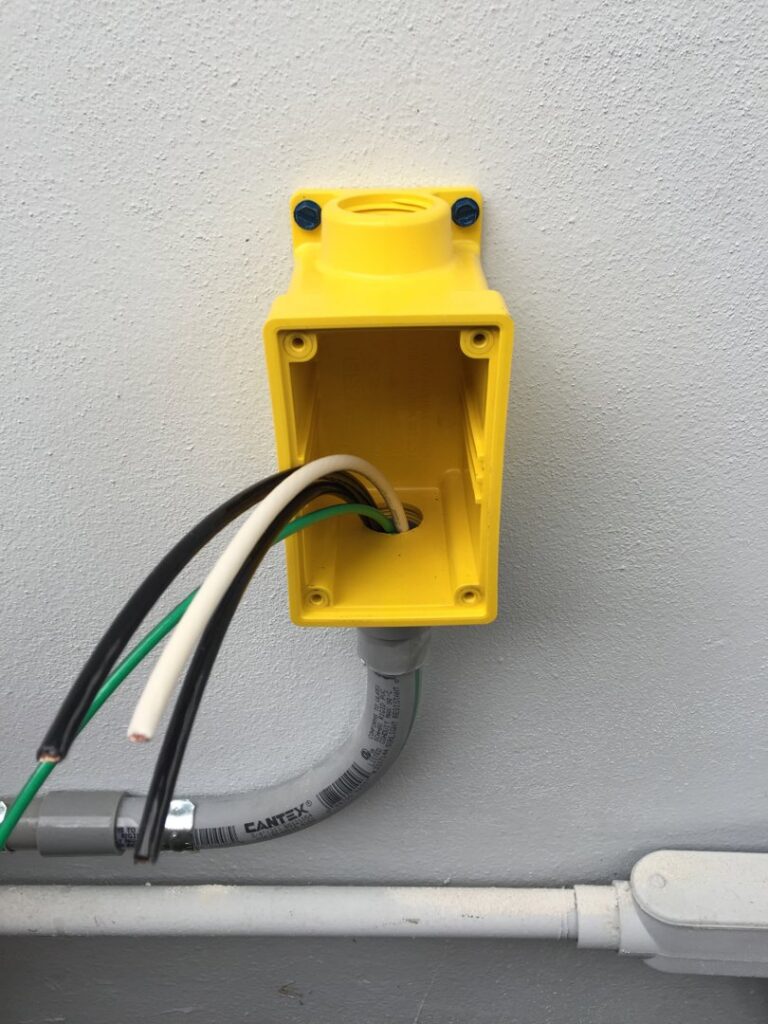 An open yellow electrical box with wires being installed through conduit by MG ELECTRIC INC in Lauderhill, FL