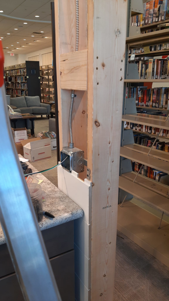 An electrical box and conduit being installed within a wooden column by Ostberg Electrical Solutions in Idaho Falls, ID.