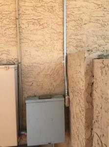 Newly installed electrical conduit and a service box on a building exterior by Earth Electric in Mesa, AZ