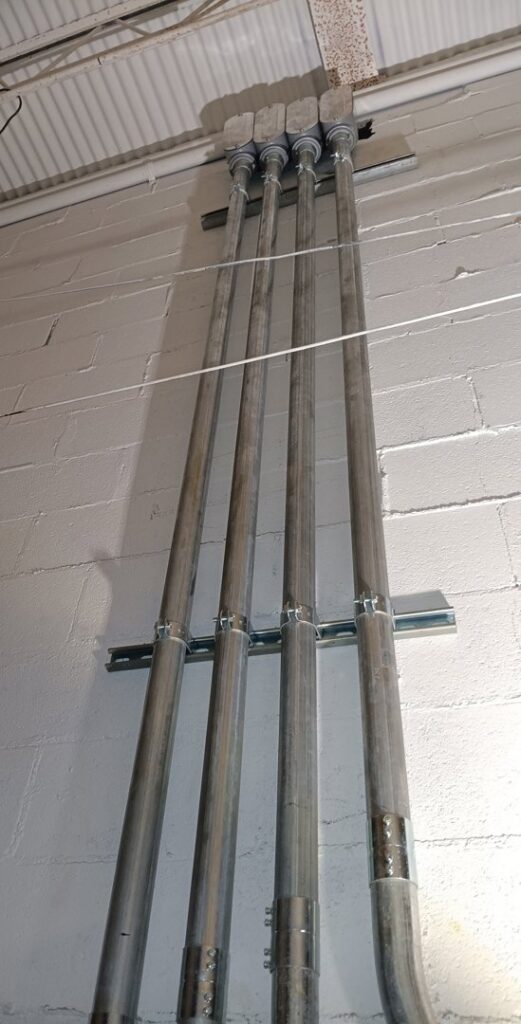 Vertical installation of multiple electrical conduits on a white brick wall by Delta Electric in Germantown, MD.