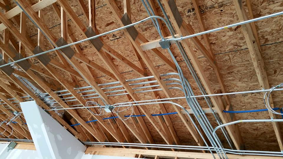 Extensive electrical conduit installation on exposed wooden trusses in a building under construction by Ready Electric 24/7 in Knoxville, TN.