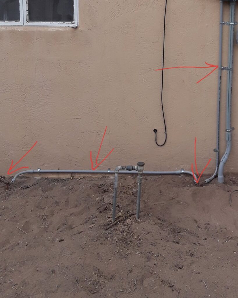 Exterior electrical conduit installation along a building wall and ground, indicating professional work by Certified Electrician Albuquerque NM.