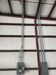Electrical conduit installation leading to multiple panels on a wall by Overton Power Solutions Electric in Hephzibah, GA