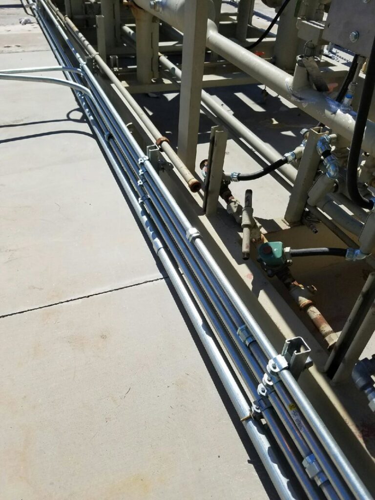 Newly installed electrical conduit pipes running along an outdoor structure by Turn It On Electric in Phoenix, AZ