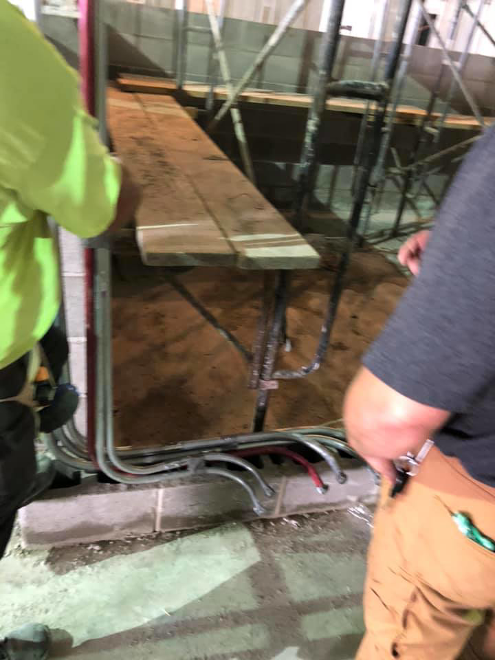 Electrical conduits being installed along a wall at a construction site by Azure Electrical in Indianapolis, IN