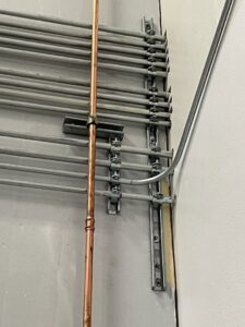 Electrical conduits and a copper pipe installed neatly along a wall by Ernco Electric Inc. in Fresno, CA.