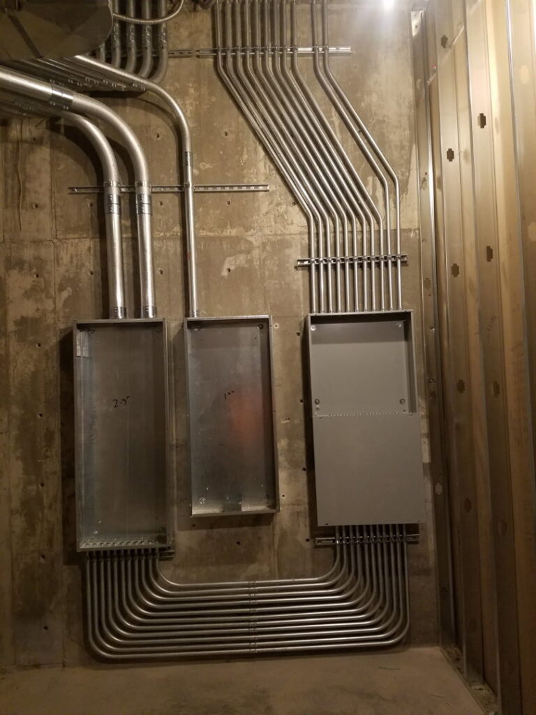 Neatly installed electrical conduits and junction boxes on a concrete wall, showcasing work by Bottom To The Top Electric LLC in Lakewood, CO.