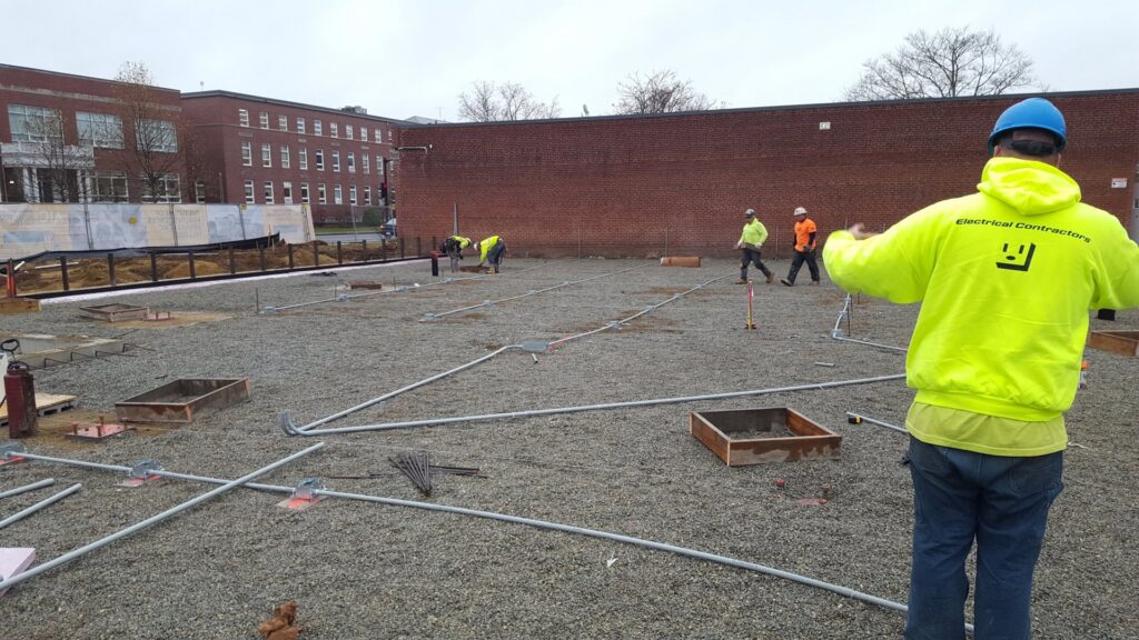 Electricians laying out electrical conduits on a construction site, performed by Icon West Corporation Electrical Contractors in Springfield, MA.
