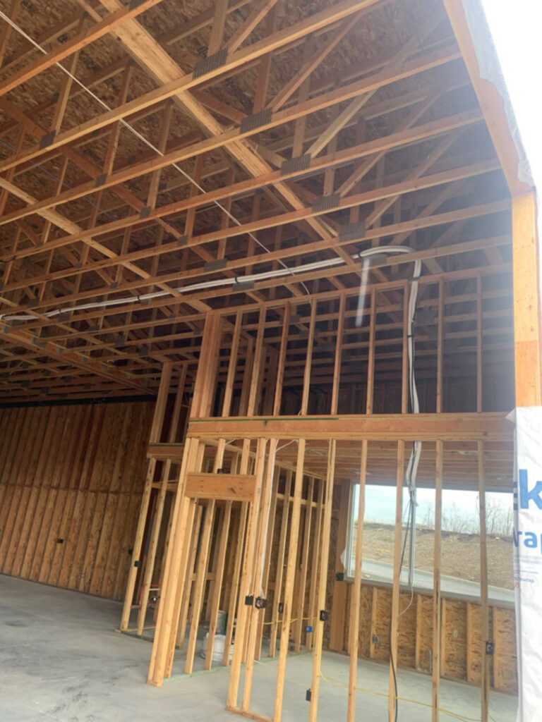 Electrical conduit and wiring running along the ceiling during rough-in in a building under construction by Interstate Electrical Contractors in Dalton Gardens, ID.