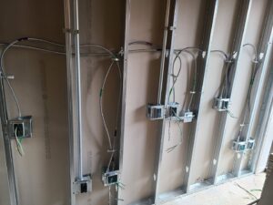 Electrical conduit and wiring installed within wall studs during construction, demonstrating rough-in work by 8Thirty Electric, Inc. in Johns Creek, GA.