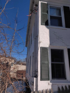 Exterior electrical conduits and wiring running along a house, installed by Lindquist Electric in Upton, MA.