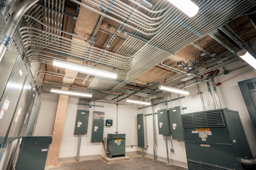 A room showcasing extensive electrical conduits, panels, and lighting installations by BESCO in Knoxville, TN.