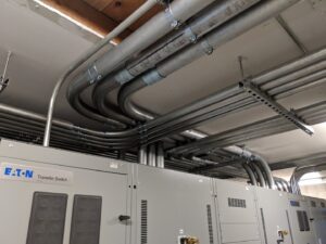 Multiple electrical conduits and transfer switches installed in an industrial setting by Trademark Elite Electrical Services in Butte, MT