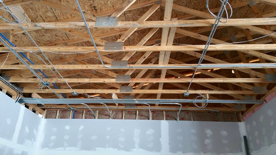 Electrical conduits and wiring installed across exposed wooden ceiling trusses during construction by Ready Electric 24/7 in Knoxville, TN.