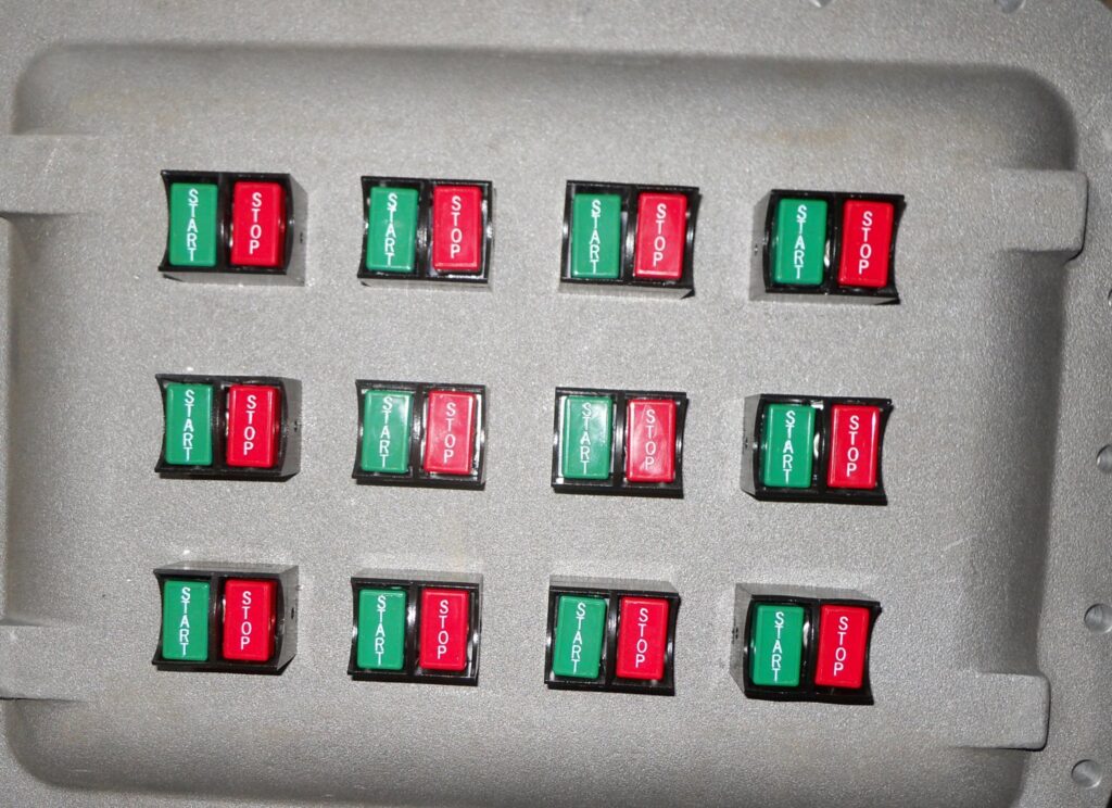 An electrical control panel featuring multiple "Start" and "Stop" buttons for industrial machinery, provided by Basic Supply in Lafayette, LA.