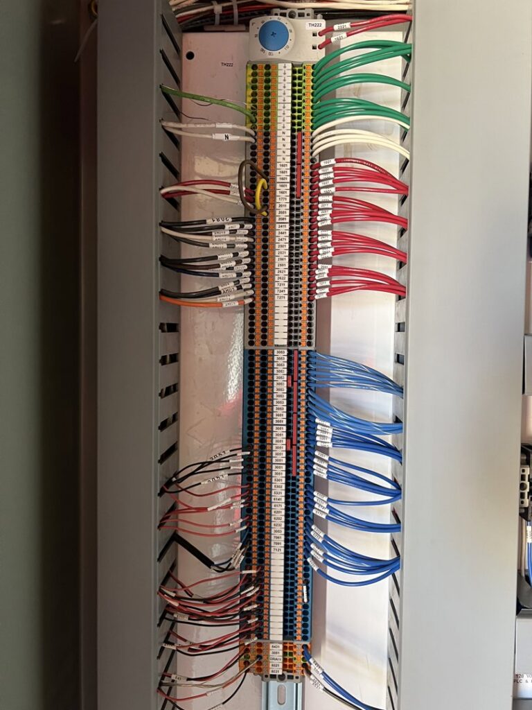 An open electrical control panel with intricate wiring and terminals, demonstrating expert work by Veritas Electric in Yalaha, FL.