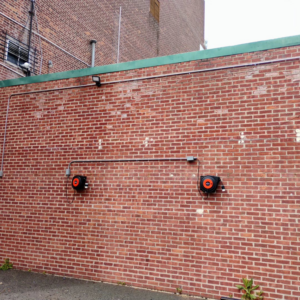 Two electrical cord reels and conduit installed on a brick wall by C&J And Sons Multi Services in Newark, NJ.